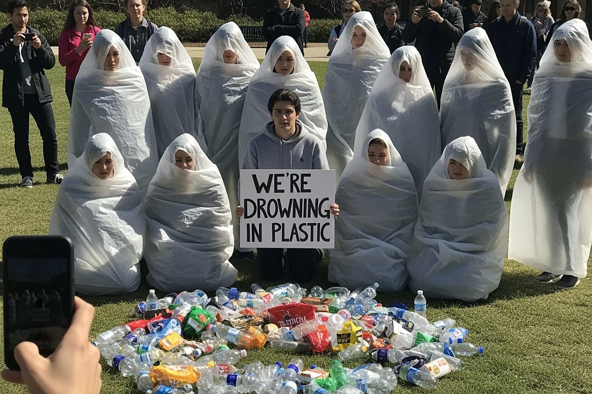 Close-up of a person's hand wrapped in clear plastic film, symbolizing pollution.