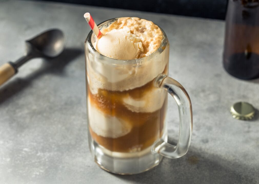 Ice cream sodas Clear glass mug with brown liquid and ice cream scoops floating.