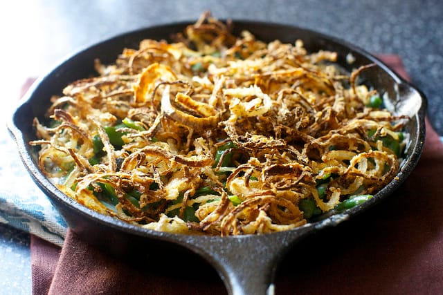 chef plating a green bean casserole with crispy fried onions