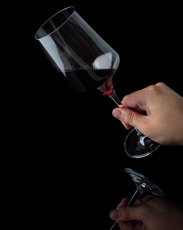 glass of red wine with a person's hand holding it