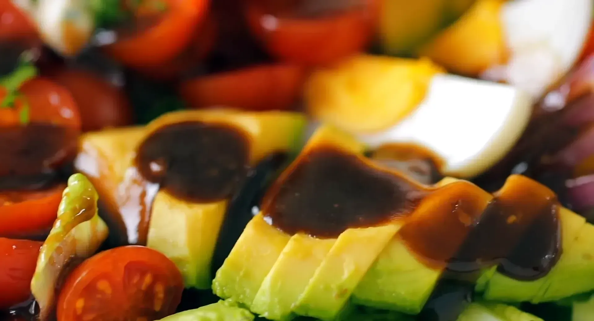 Drizzling dressing over the salad.