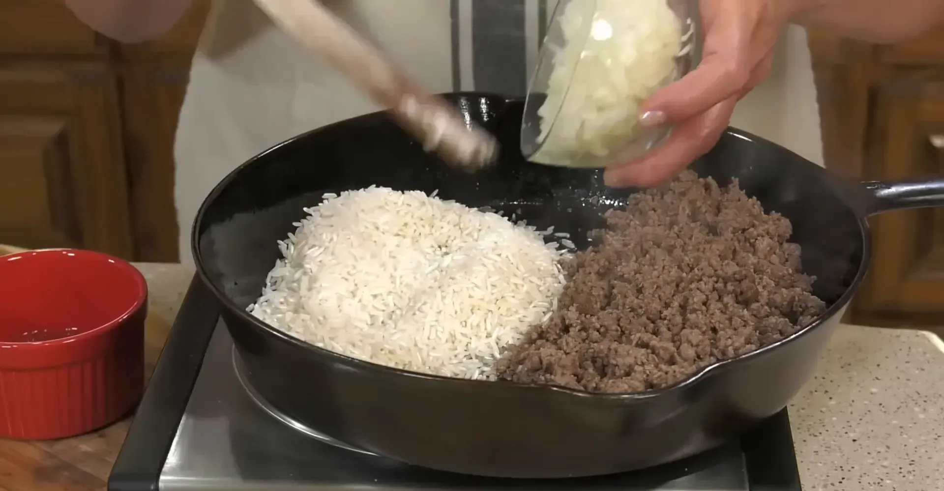 Adding rice and onions to the skillet