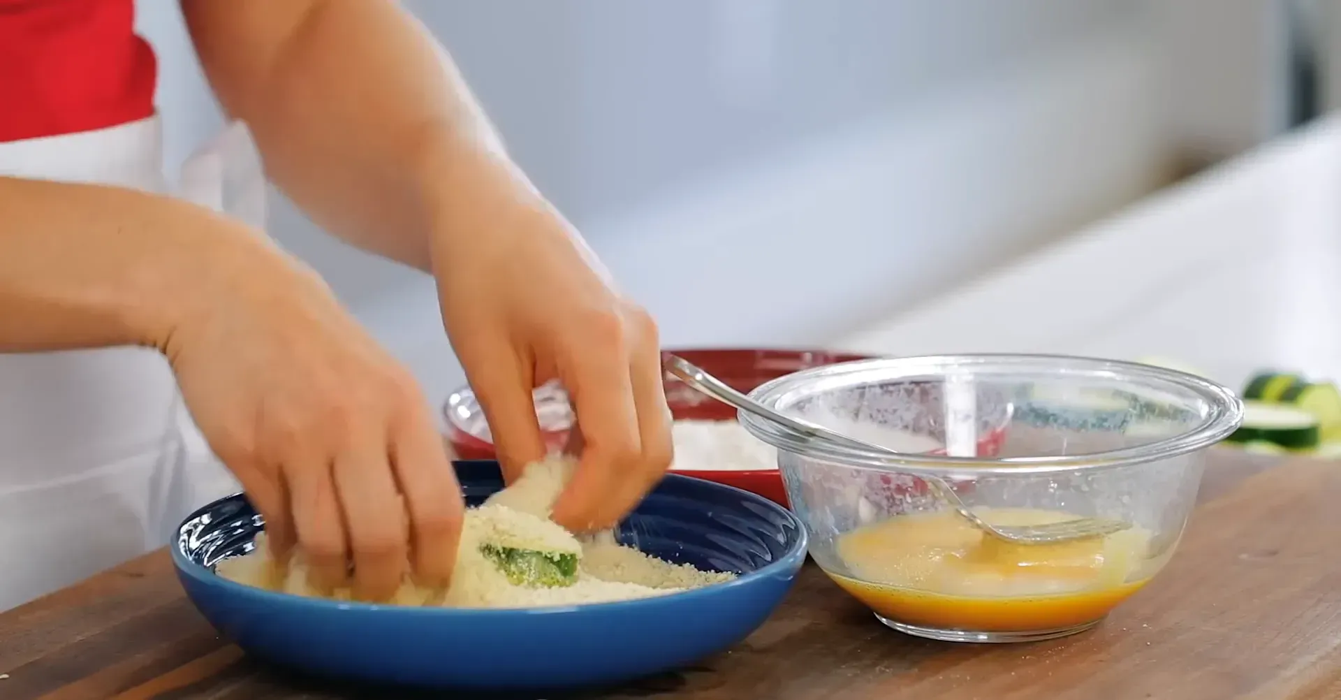 Coating zucchini in breadcrumbs.