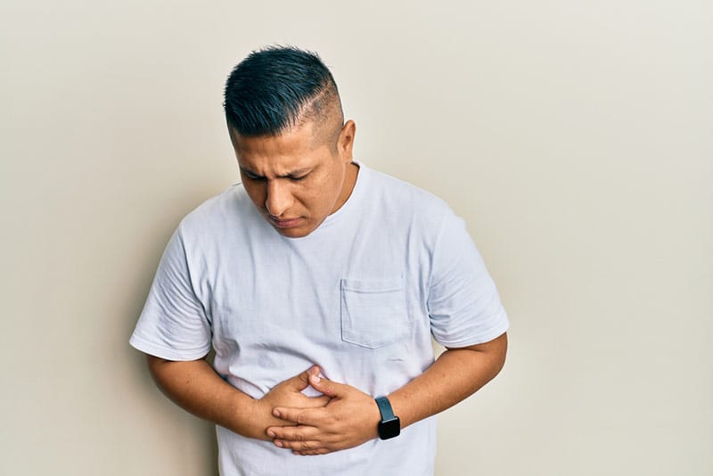 person with stomach ache reaching for medicine