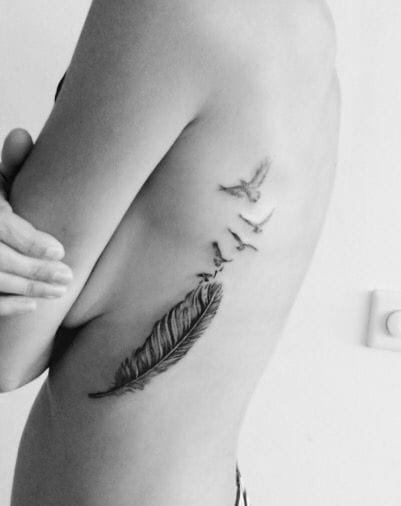 a ribs tattoo with a feather and birds