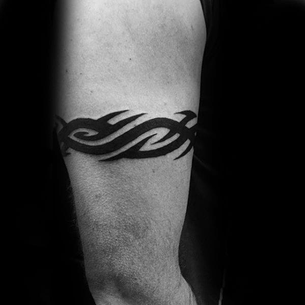 a masculine upper arm tattoo with tribal band