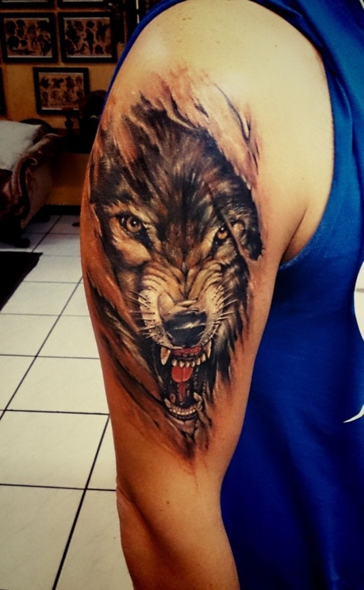 an upper arm tattoo with a wolf head