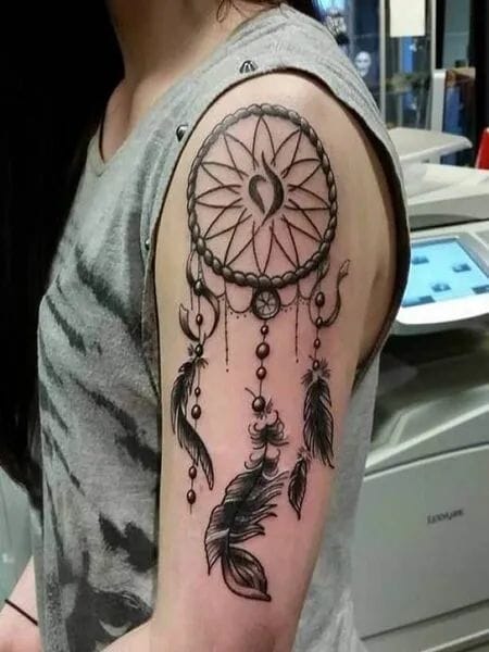 an upper arm tattoo with a dreamcatcher