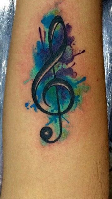 upper arm with music notes tattoo with watercolor splashes