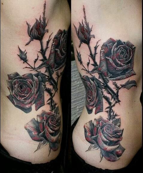 a rib tattoo with a rose, thorns, and leaves
