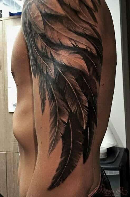 upper arm with feather tattoo in black and grey realism