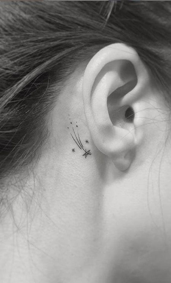 a delicate shooting star tattoo behind ear