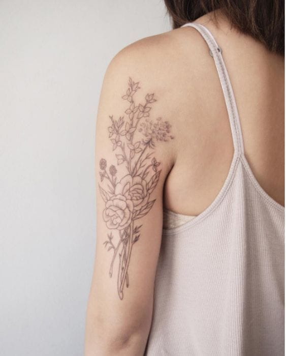 upper arm with minimalist fine line botanical tattoo