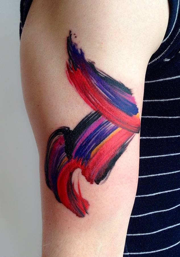 upper arm with abstract brushstroke tattoo in vivid colors