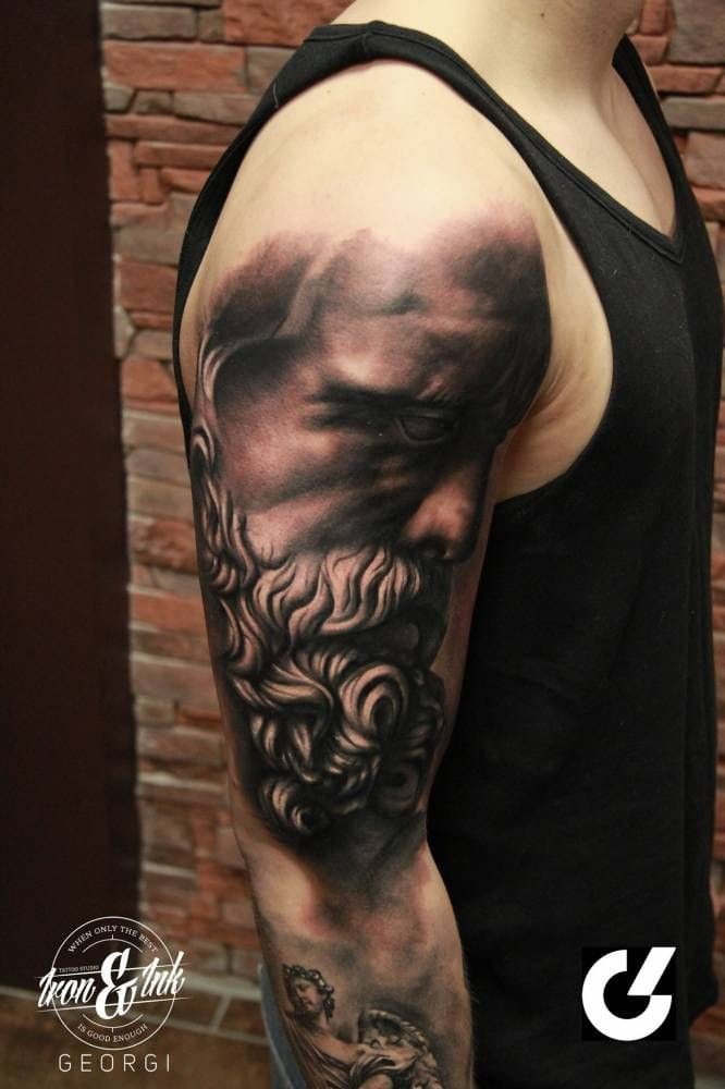 a muscular upper arm tattoo with black and grey portrait