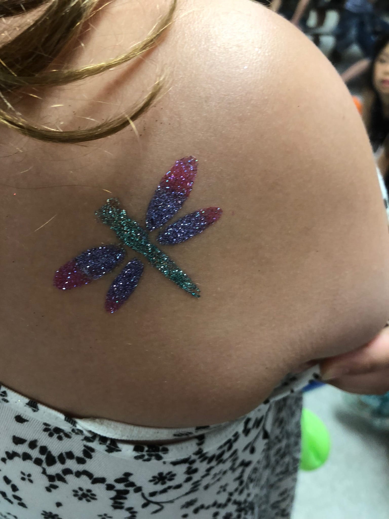 a dazzling glitter tattoo with a dragonfly
