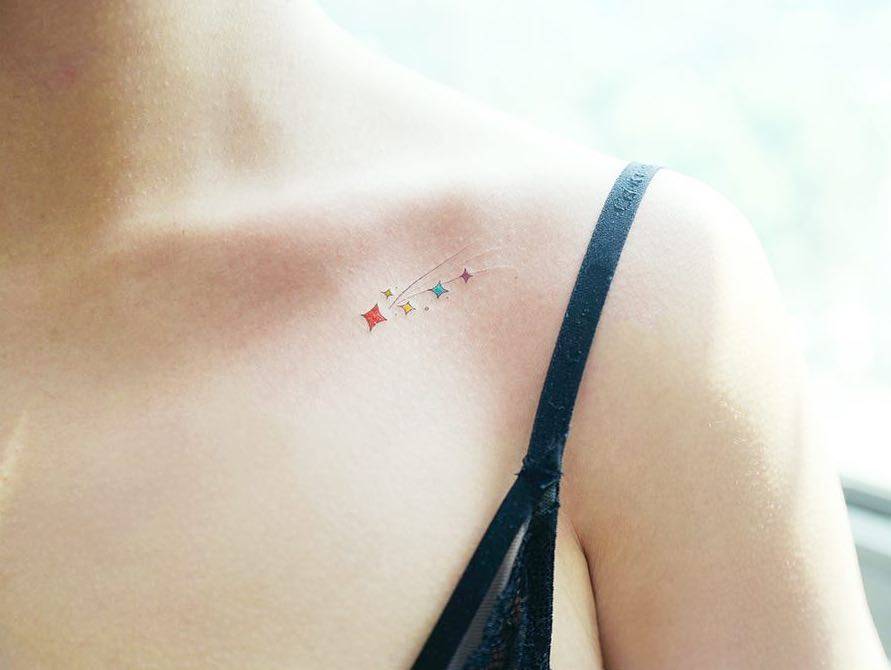 a delicate shooting star tattoo on collarbone