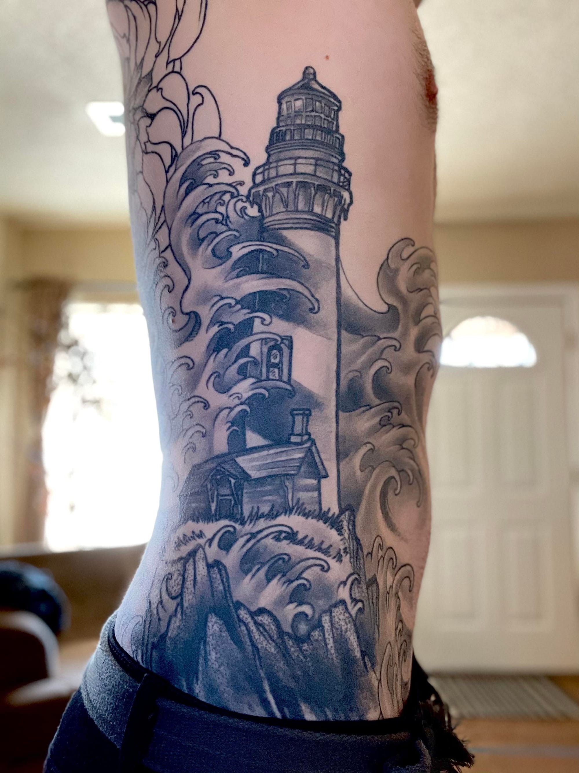 a ribs tattoo with a lighthouse and waves