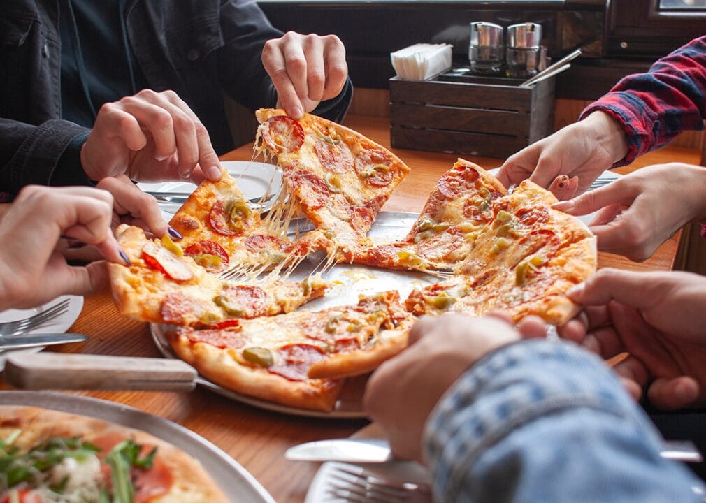 People sitting at a table eating pizza.