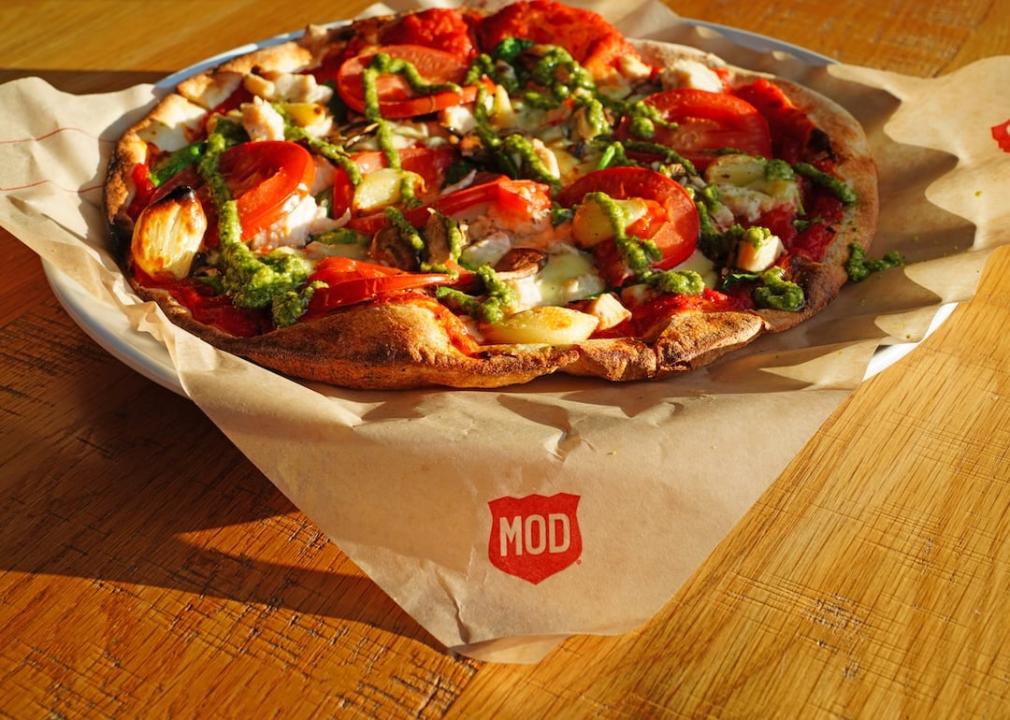 An individual pizza on a wood table at MOD Pizza restaurant.