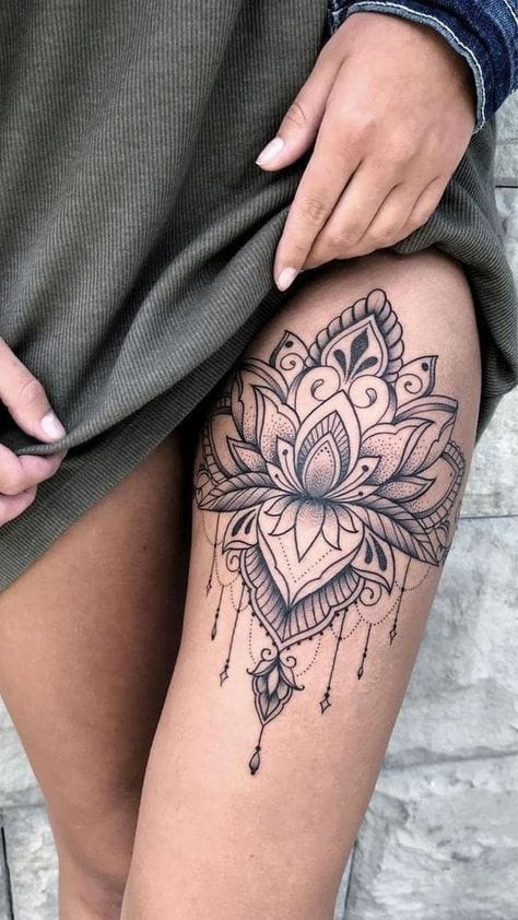 Delicate mandala petals cascade down this thigh in an enchanting display of ornate linework and geometric precision. The intricate lotus design flows seamlessly from bold floral elements into dangling decorative chains, creating a stunning piece that perfectly follows the natural curve of the leg. This sophisticated black ink masterpiece transforms the thigh into a canvas of spiritual artistry ✨