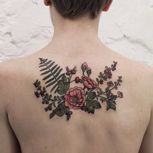 Delicate botanical artistry blooms across this person's upper back, featuring a stunning arrangement of pink roses intertwined with ferns and trailing greenery. The soft, muted color palette and intricate linework create an almost vintage botanical illustration effect that feels both timeless and deeply feminine. 🌹 The asymmetrical composition flows naturally with the body's contours, making this piece feel like a living garden pressed into skin.