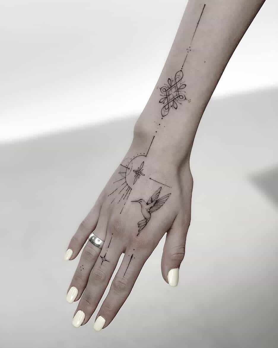 Delicate fine-line artistry transforms this hand and forearm into a celestial roadmap, where geometric florals bloom alongside a graceful hummingbird caught mid-flight. The strategic placement creates beautiful movement as the design flows from wrist to fingertips, with tiny dotwork stars and linear elements that seem to shimmer against the skin ✨