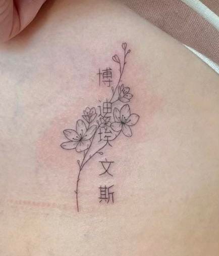 Delicate line work transforms skin into a canvas where botanical beauty meets Eastern calligraphy in this stunning ribcage piece. The flowing vine seems to grow organically around the vertical Chinese characters, creating a harmonious dance between nature and language that speaks to both artistic sophistication and personal meaning. 🌿