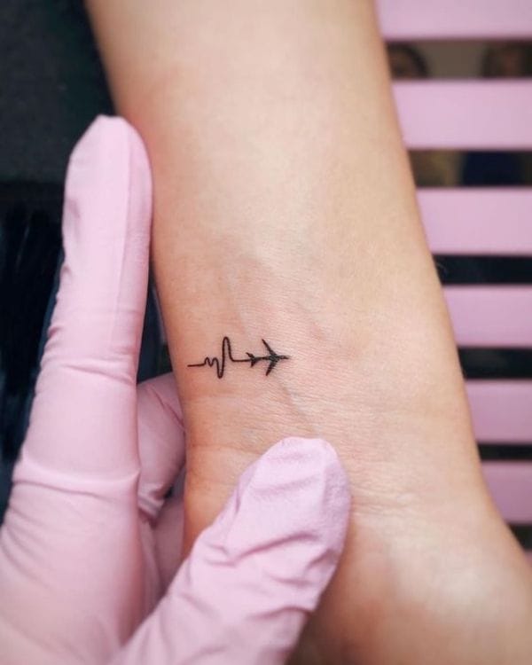 Wanderlust meets vitality in this delicate wrist piece where a heartbeat line seamlessly transforms into soaring aircraft ✈️ The minimalist black ink design captures that rush of excitement when adventure calls, perfectly positioned to catch your eye every time you check the time. Clean linework and thoughtful symbolism make this tiny tattoo a powerful reminder that travel truly makes the heart beat faster.