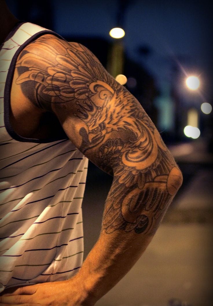 Fierce mythical creatures come alive in this stunning sleeve masterpiece, where intricate linework and masterful shading create depth that seems to move with every muscle. The dramatic evening lighting perfectly captures the tattoo's dimensional quality, transforming this arm into a living canvas of Eastern-inspired artistry. 🐉