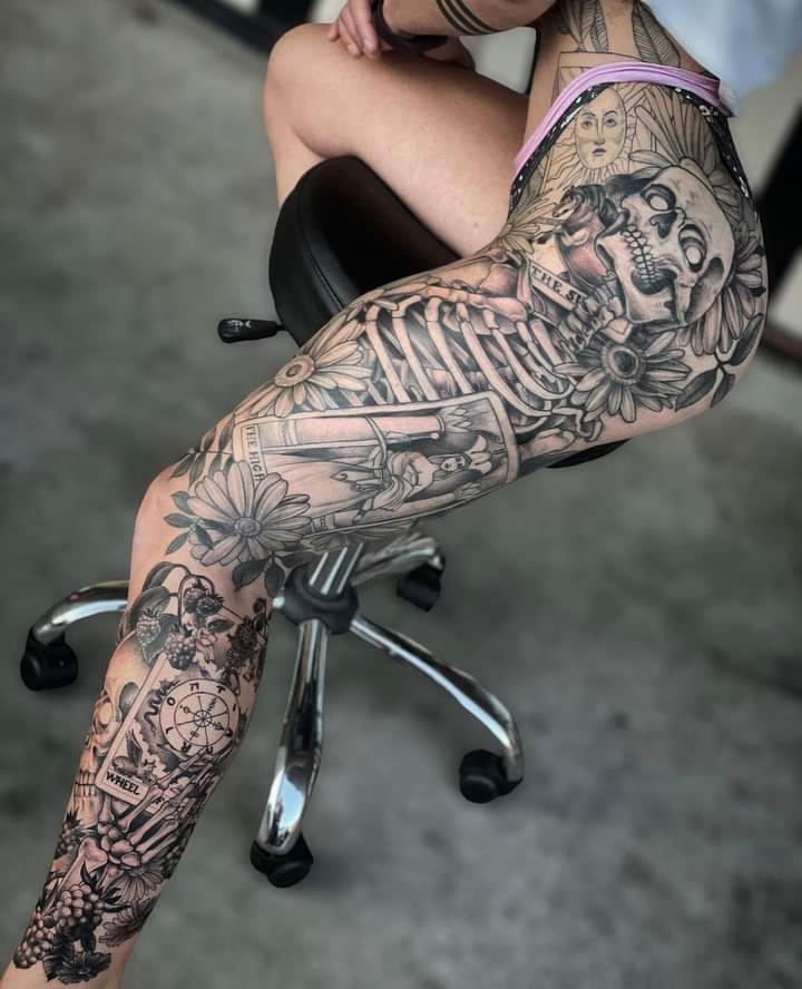 Dark artistry flows seamlessly across this full leg masterpiece, where intricate skeletal figures dance alongside celestial suns and delicate florals in perfect Gothic harmony. The exceptional line work and shading create a mesmerizing contrast between life and death motifs, transforming the entire limb into a walking canvas of macabre beauty ☠️
