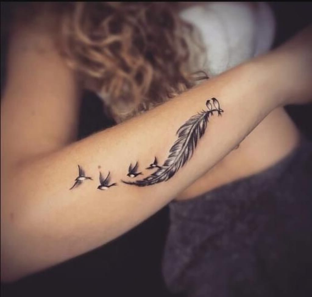 A delicate feather gracefully transforms into a flock of soaring birds along this person's forearm, creating a mesmerizing flow that follows the natural curve of their arm. The fine line work and organic placement make this piece feel like it's actually floating on the skin, while the symbolic journey from feather to flight speaks to themes of freedom and transformation ✨