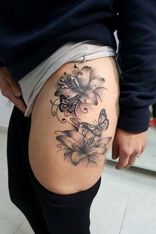 Delicate lilies cascade down this thigh placement like a botanical waterfall, intertwined with graceful butterflies that seem to dance between the blooms. The fine line work and soft shading create an almost ethereal quality, while the curved composition follows the natural contours of the leg beautifully 🦋