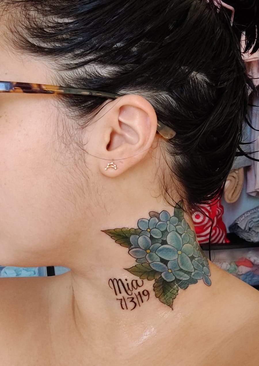 Delicate hydrangea blooms cascade down this neck placement, creating a stunning botanical masterpiece that perfectly complements the natural curve of the shoulder. The soft blue petals are rendered with incredible detail, while the accompanying script adds a personal touch that makes this floral design truly one-of-a-kind. 🌸 The artist's skillful shading brings each petal to life with remarkable depth and dimension.