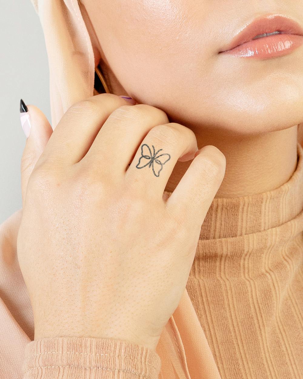 Delicate linework transforms this ring finger into wearable art with a minimalist butterfly that dances across the knuckle. The fine black ink creates an ethereal outline that feels both whimsical and sophisticated, proving that the smallest tattoos can make the biggest statement 🦋