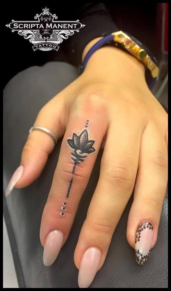 Delicate botanical artistry transforms this finger into a living canvas, featuring a stunning lotus bloom connected to minimalist line work and dotted details. The vertical placement along the middle finger creates an elegant elongated effect that's both subtle and striking—perfect for those who want meaningful ink that whispers rather than shouts. 🌸