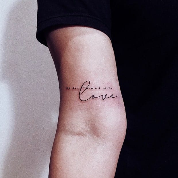 Delicate script flows across the forearm like handwritten poetry, transforming skin into a canvas for life's most essential philosophy. The elegant cursive lettering 