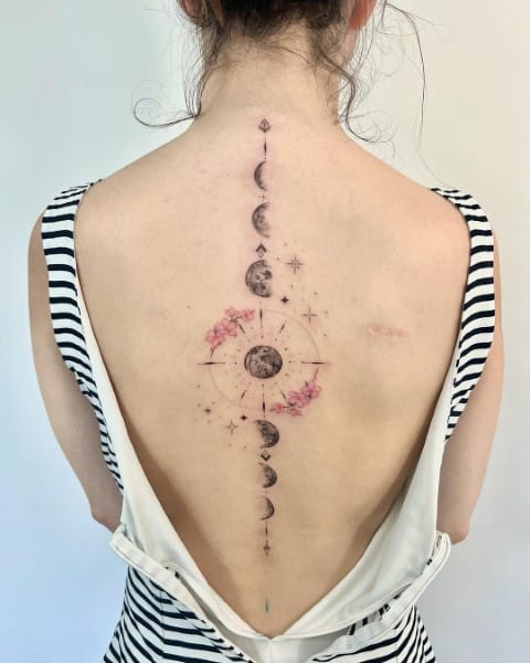 Cascading down the spine like celestial poetry, this ethereal moon phase tattoo transforms the back into a canvas of cosmic wonder. The delicate watercolor florals blooming around the central moon create a dreamy contrast against the precise lunar silhouettes, making this piece feel both grounded and otherworldly ✨