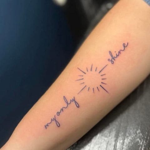 Delicate script flows around a minimalist sunburst in this beautifully balanced forearm piece, with 