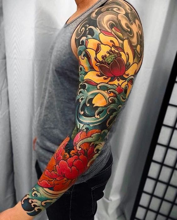 Vibrant Japanese artistry flows seamlessly down this full sleeve, where lotus blooms emerge from swirling teal waters in a stunning display of traditional irezumi technique. The masterful color saturation and dynamic wave patterns create an almost three-dimensional effect that makes each floral element appear to float above the skin. This is how you honor centuries-old tattooing traditions while making them completely your own 🌸