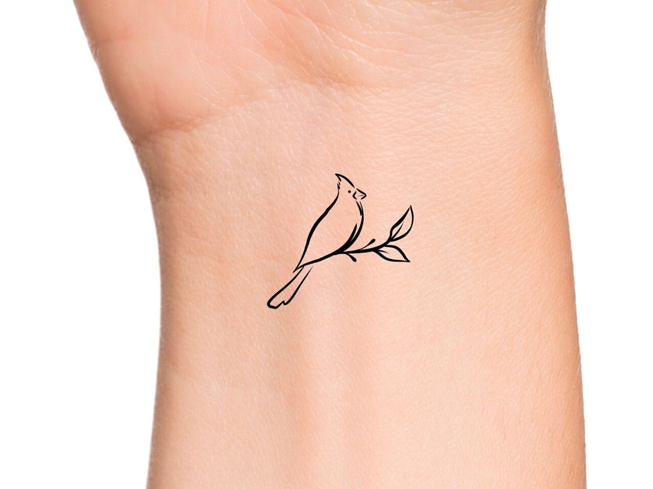 Delicate line work transforms a simple bird perched on a branch into pure minimalist poetry on this wrist placement. The cardinal's distinctive crest and graceful posture create a stunning silhouette that flows beautifully with the natural curves of the arm, while the subtle botanical element adds organic balance to this timeless design 🕊️