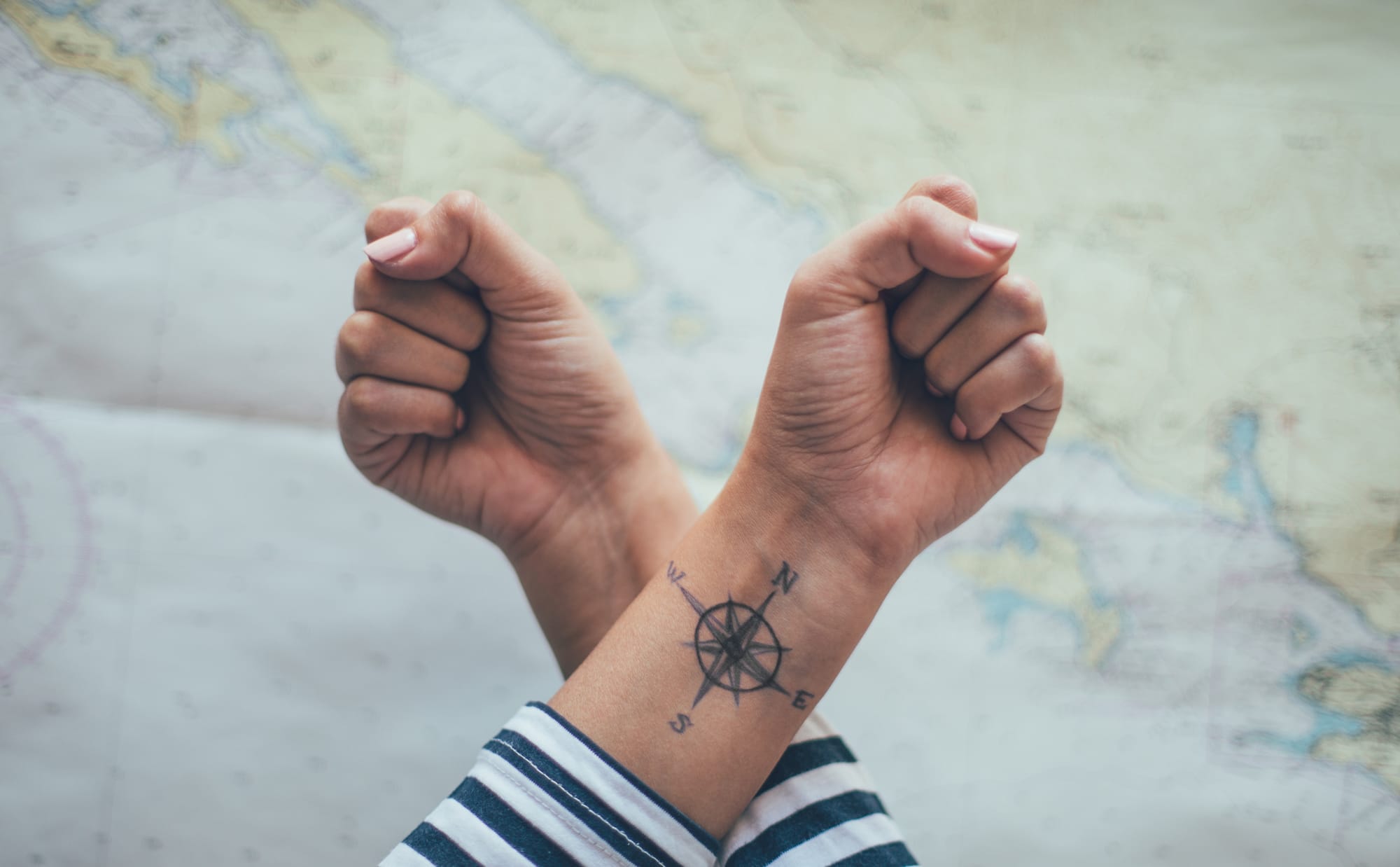 Adventure calls from this beautifully placed compass tattoo that transforms an ordinary wrist into a navigation tool for life's journey. The crisp black linework and classic nautical design create perfect harmony against the map backdrop, while the strategic placement between both hands symbolizes having direction literally at your fingertips ⚓ Whether you're a wanderlust soul or simply love the timeless symbolism of finding your true north, this piece proves that the best tattoos guide us both outwardly and inward.
