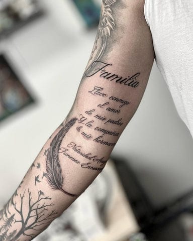 Delicate script flows seamlessly between ethereal feather motifs in this stunning forearm piece, creating a poetic narrative that wraps around the arm like whispered secrets. The masterful integration of text and organic elements showcases how meaningful words can become part of a larger artistic story, with each feather appearing to carry the sentiment forward. 🪶