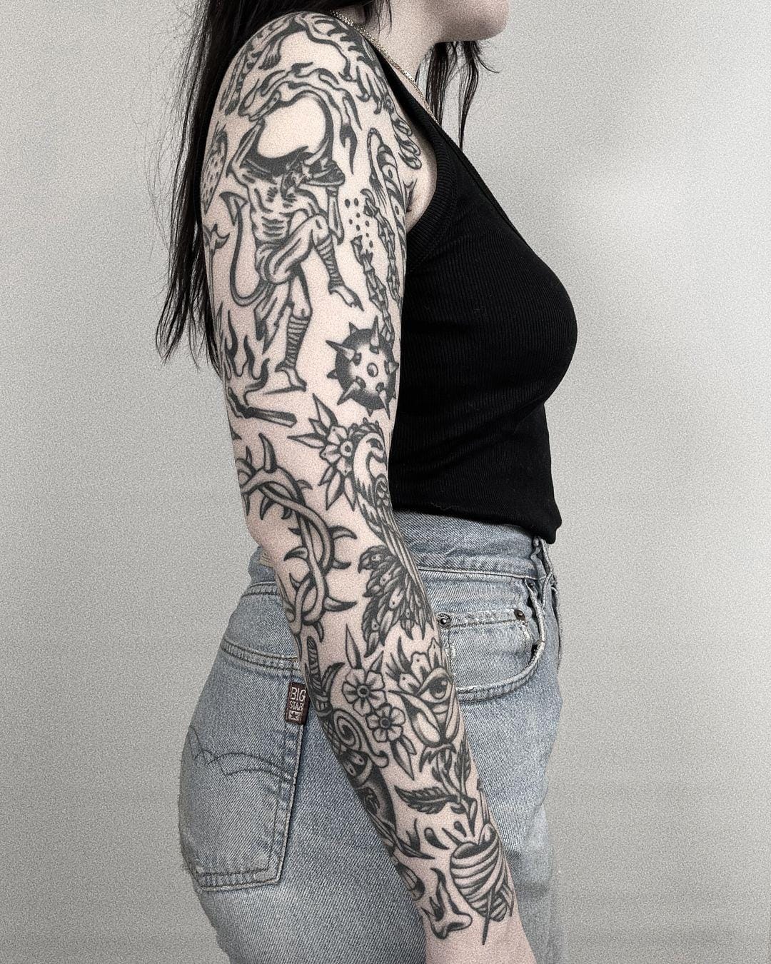 Dark botanical elements cascade down this striking full sleeve, weaving together delicate florals with gothic motifs in gorgeous black linework. The intricate design flows seamlessly from shoulder to wrist, creating a cohesive narrative that perfectly complements the natural curves of the arm 🖤 Such masterful composition and detail work!