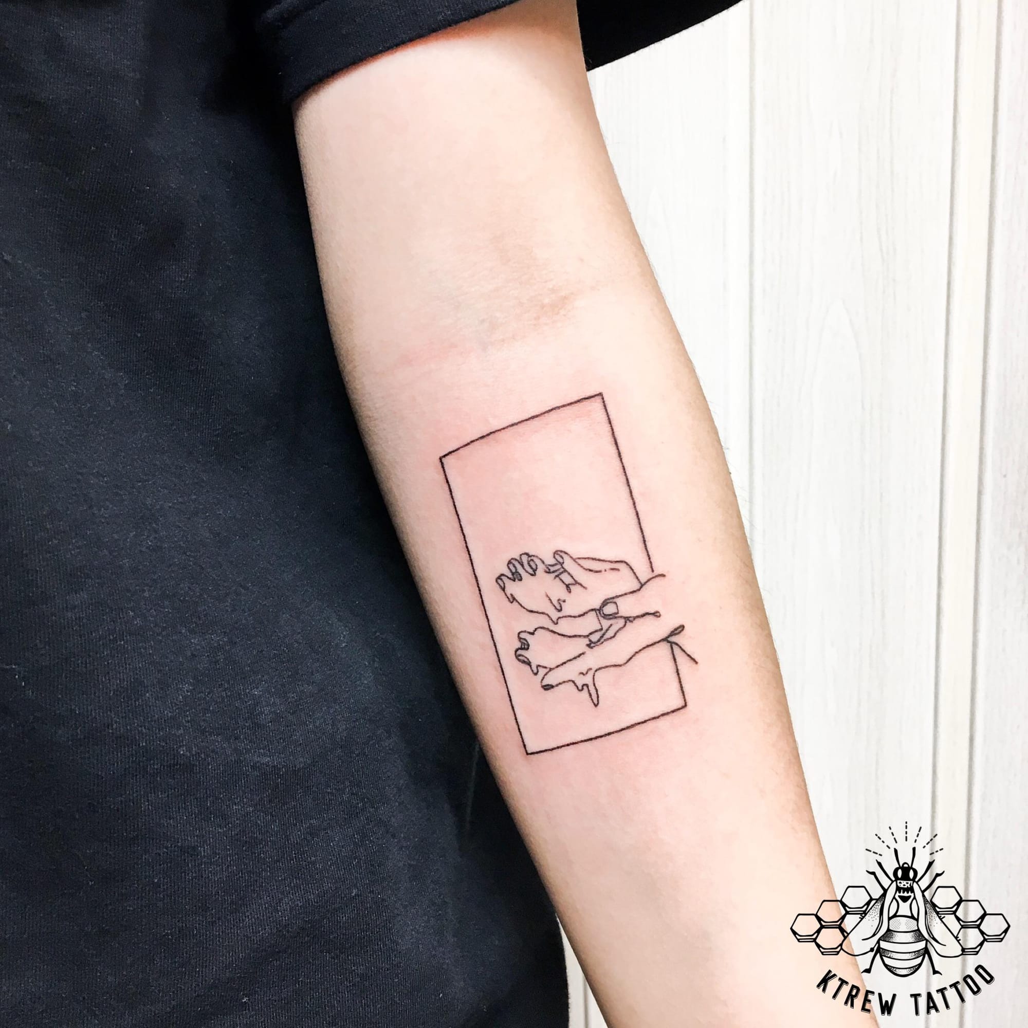 Delicate line work transforms this forearm into a canvas for intimate storytelling, where two figures embrace within the confines of a simple rectangular frame. The minimalist approach creates a polaroid-like effect that feels both nostalgic and deeply personal, as if capturing a fleeting moment of tenderness frozen in ink. Perfect placement on the inner forearm ensures this sweet reminder stays close to the heart 💕
