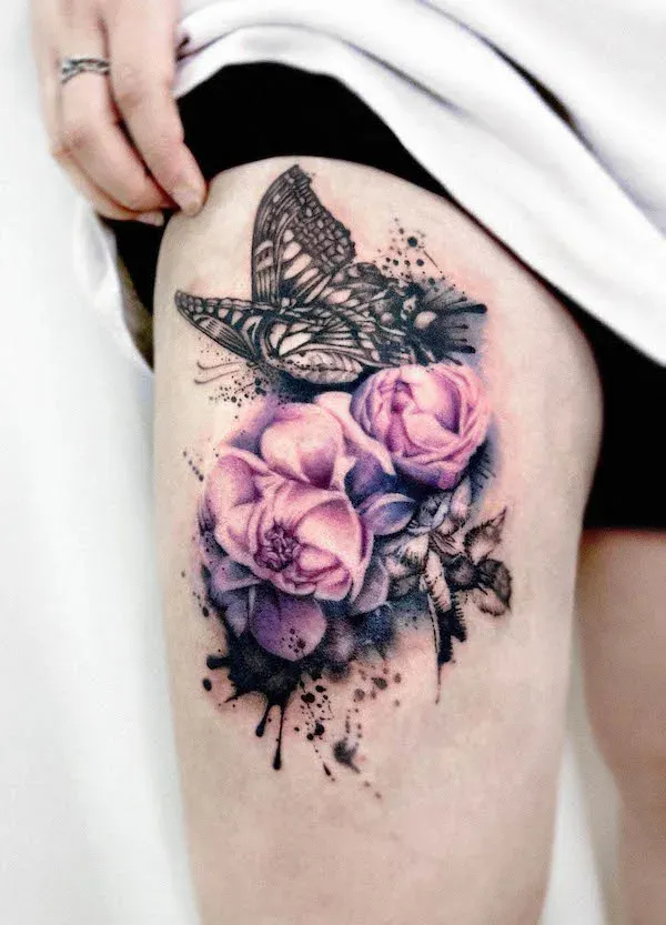 Delicate watercolor splashes blend seamlessly with bold linework in this stunning thigh piece, where a detailed butterfly appears to have just landed on a bouquet of soft purple roses. The artist's masterful use of color gradients creates an almost dreamy, ethereal quality that makes the florals appear to bloom right off the skin. The strategic placement allows for beautiful flow and movement, turning the natural curve of the thigh into the perfect canvas for this nature-inspired masterpiece. 🦋
