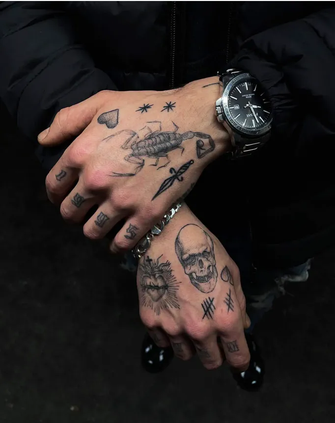 Bold blackwork adorns both hands in this striking display of symbolic ink, featuring a detailed scorpion centerpiece surrounded by stars, celestial elements, and intricate linework. The opposite hand showcases equally compelling imagery with a skull, radiating sun design, and geometric patterns that create perfect symmetry across both palms. Hand tattoos like these require serious commitment and exceptional artistry - the crisp detail work and cohesive design flow demonstrate masterful tattooing at its finest ⚡