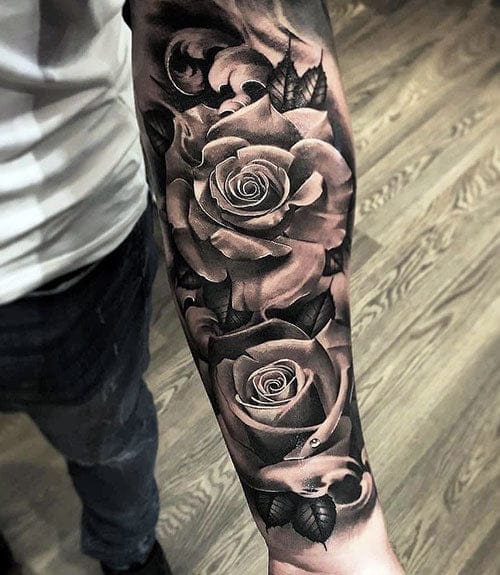 Dramatic black and grey roses cascade down this forearm in stunning photorealistic detail, each petal rendered with such precision they seem to bloom right off the skin. The masterful shading technique creates incredible depth and dimension, transforming the entire arm into a living canvas of botanical artistry. 🌹