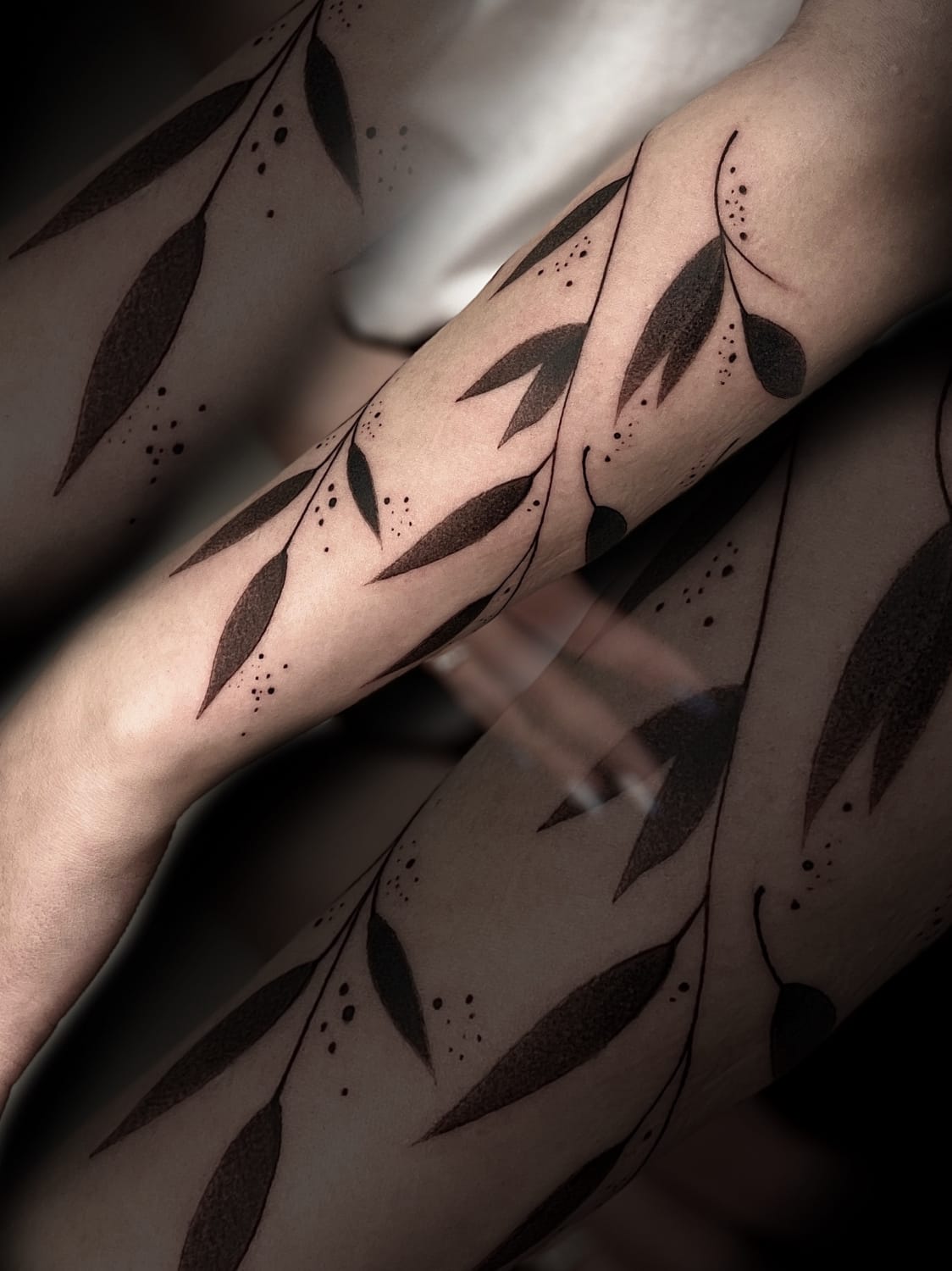 Flowing like nature's own calligraphy, this botanical blackwork creates stunning visual movement across the forearm with its organic leaf motifs and delicate dotwork details. The artist's mastery shines through the perfect balance of solid black fills and intricate stippling, transforming the arm into a canvas of natural elegance 🌿 The wraparound design follows the body's contours beautifully, making this piece feel like a living, breathing extension of the wearer's skin.