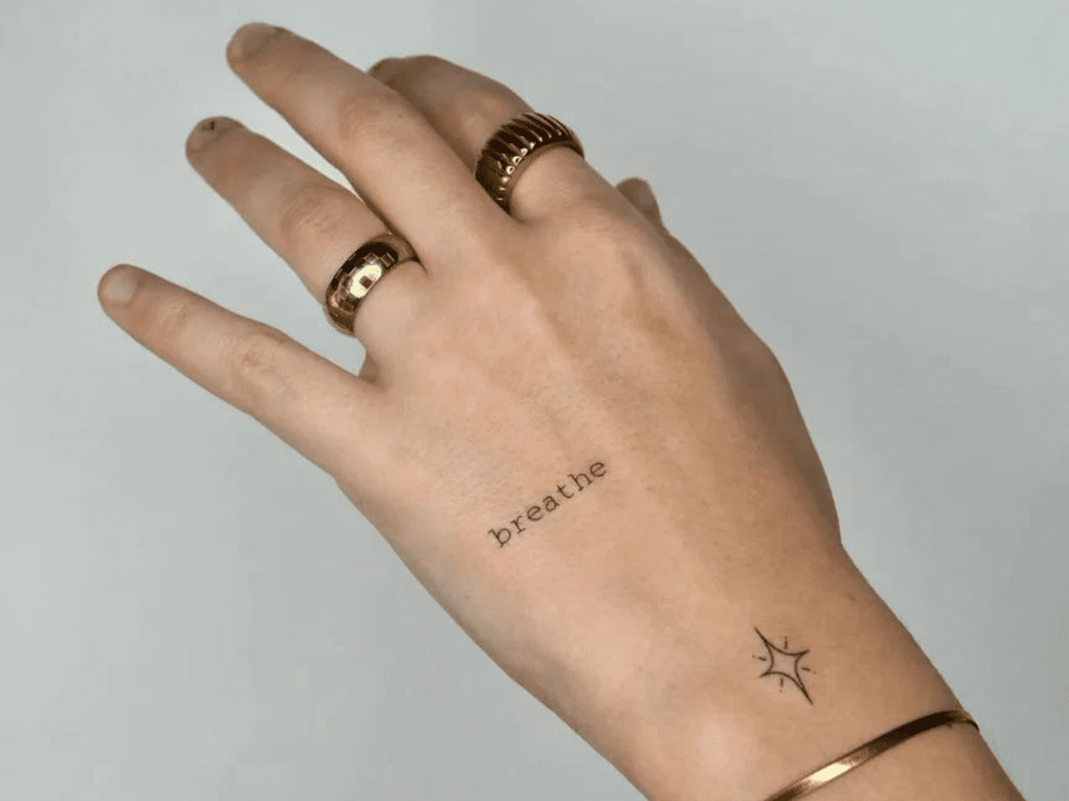 Delicate fine-line work transforms this hand into a canvas of mindful intention, featuring the gentle reminder 